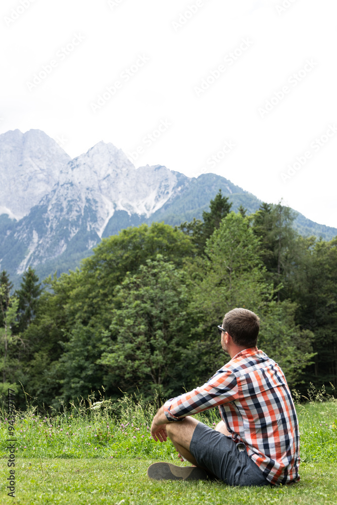 Naklejka premium Portrait of a Young Adult Man Resting in the Mountain Valley, lying on the ground