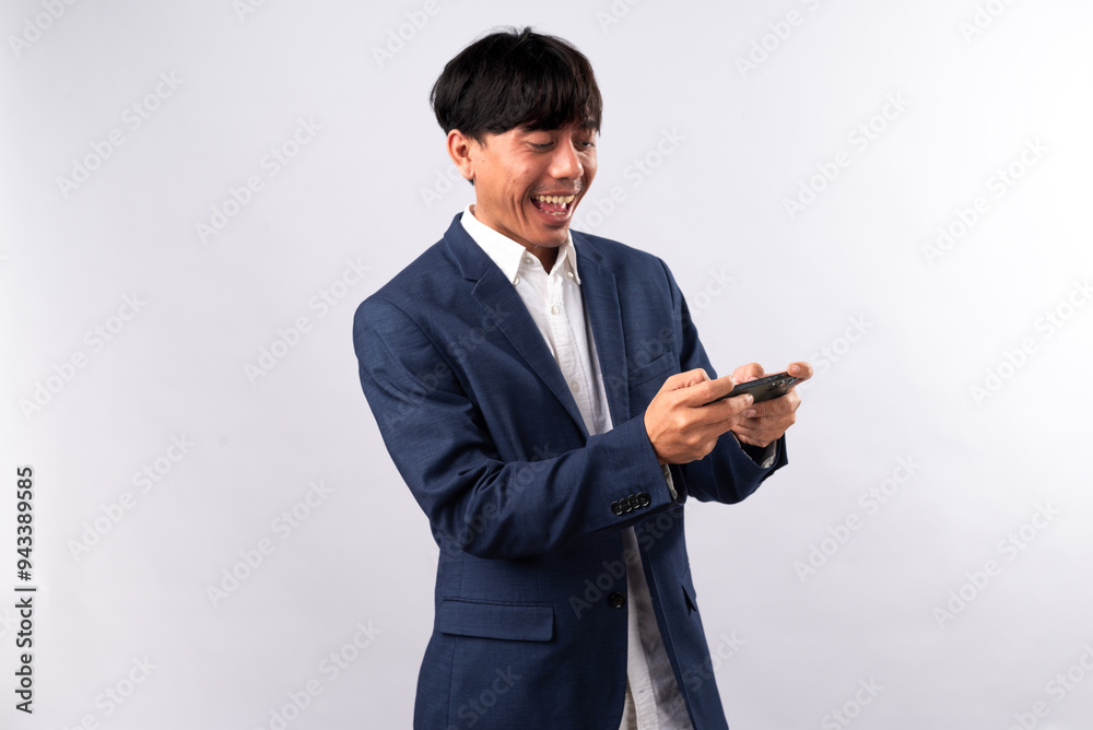 An Asian man in a blue suit excitedly reacts while using a smartphone, displaying enthusiasm and energy. He stands against a plain white background, highlighting a dynamic and tech-savvy scene. An Asian man in a blue suit excitedly reacts while using a smartphone, displaying enthusiasm and energy. He stands against a plain white background, highlighting a dynamic and tech-savvy scene.