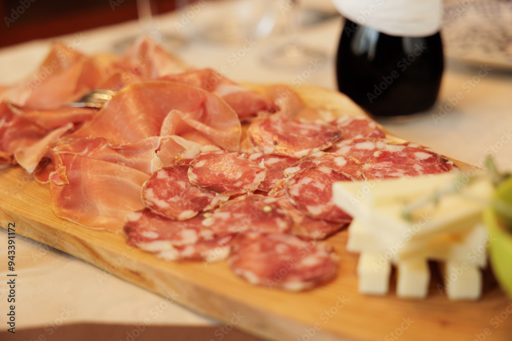 dettagli di un tagliere di legno con vari affettati di carne e fette di formaggio su un tavolo