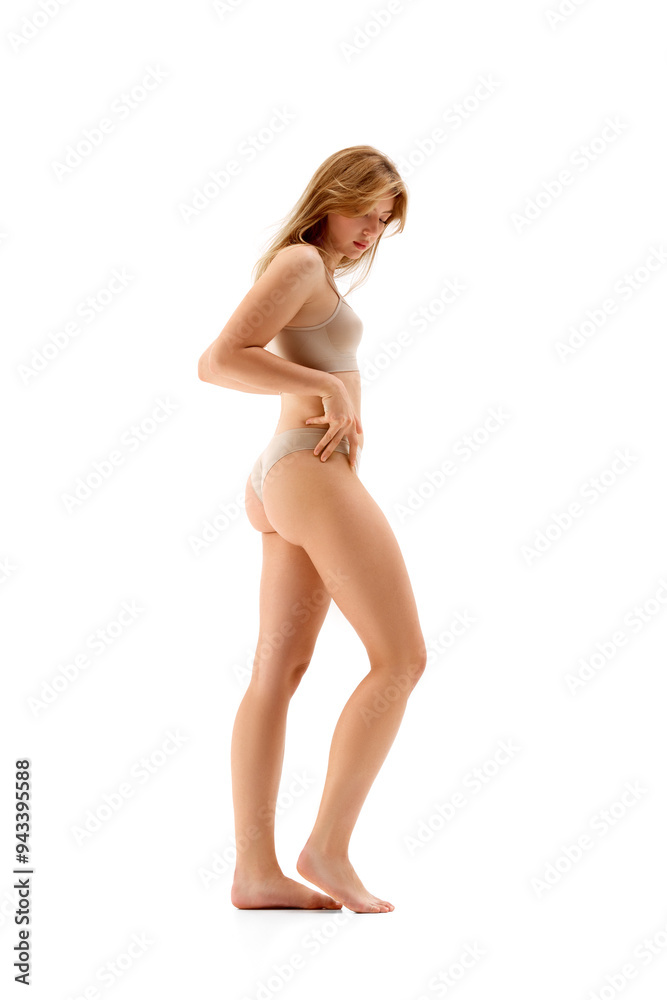 Fototapeta premium Full-length image of young attractive slim woman posing in underwear , showing her sportive, fit body, isolated on white background. Concept of female beauty, body and skin care, cosmetology, health