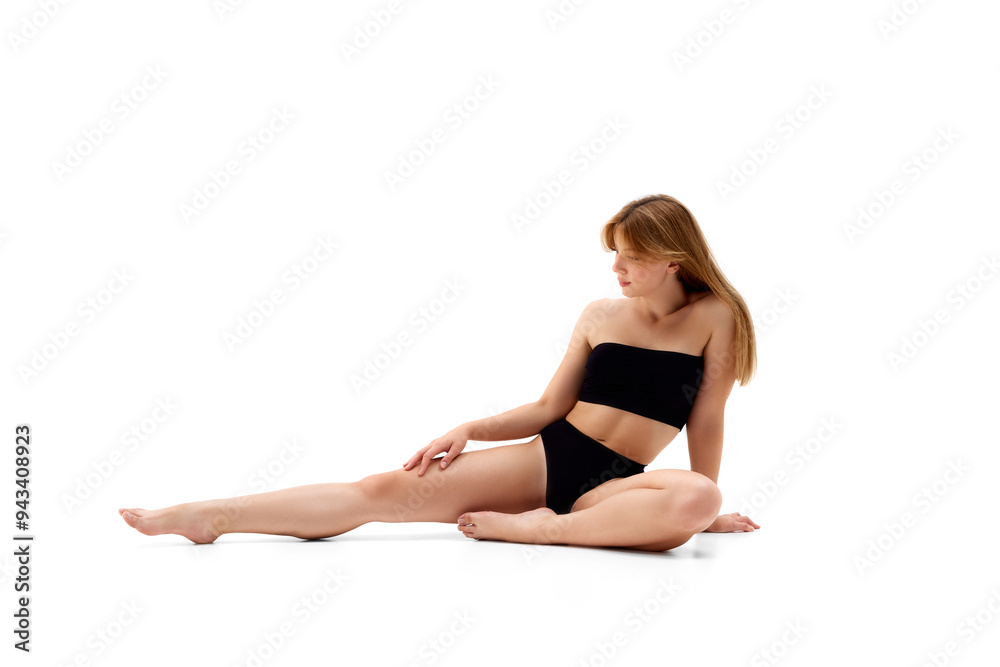 Portrait of attractive young woman with healthy sportive body, posing on floor in black underwear isolated on white background. Concept of female beauty, body and skin care, cosmetology, sport, health Portrait of attractive young woman with healthy sportive body, posing on floor in black underwear isolated on white background. Concept of female beauty, body and skin care, cosmetology, sport, health
