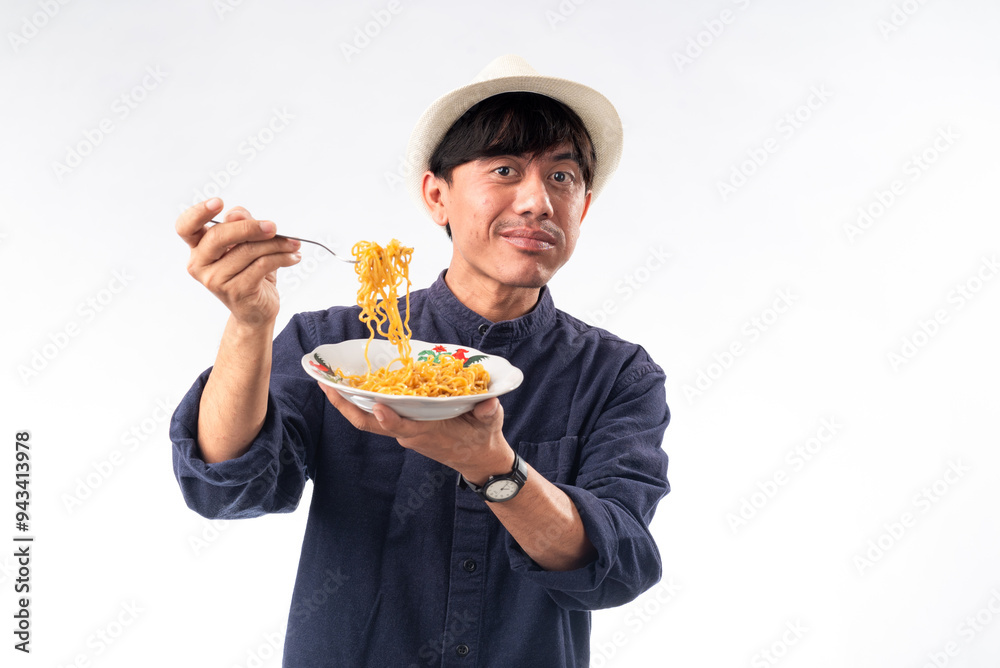 An Asian man in a dark shirt and straw hat savors noodles, his eyes closed in enjoyment. The plain white background highlights his pleasurable dining experience. An Asian man in a dark shirt and straw hat savors noodles, his eyes closed in enjoyment. The plain white background highlights his pleasurable dining experience.