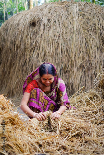 Rural woman cutting dried hays in smaller pieces for feeding domestic livestock 