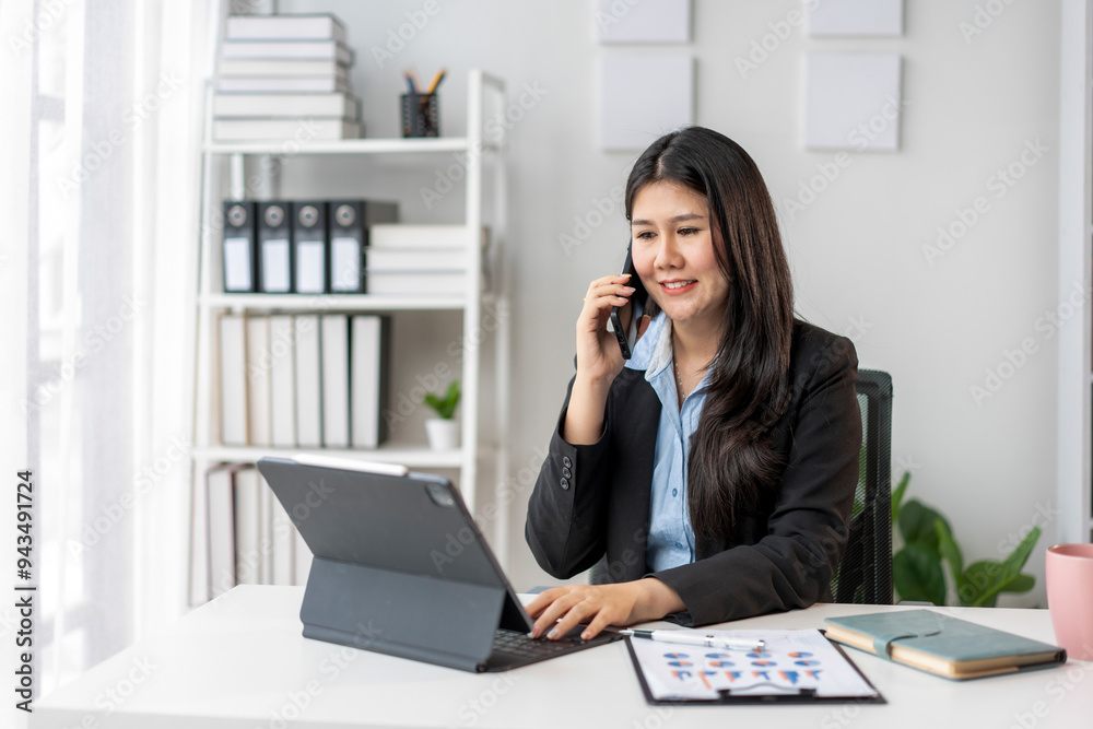 A woman is talking on her cell phone while sitting at a desk A woman is talking on her cell phone while sitting at a desk