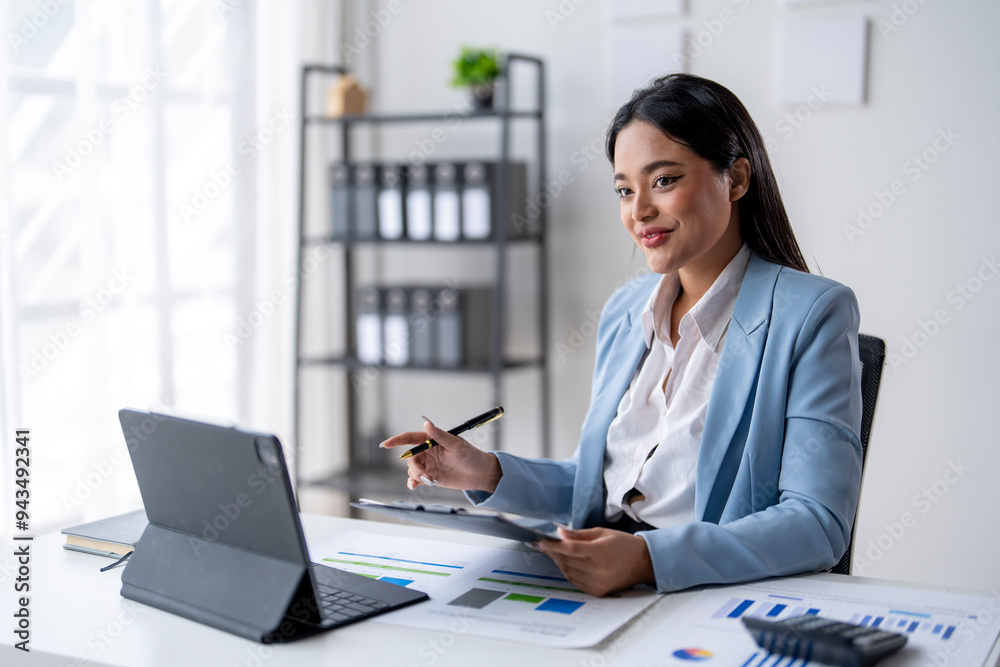 A woman in a blue suit is sitting at a desk with a laptop and a tablet A woman in a blue suit is sitting at a desk with a laptop and a tablet