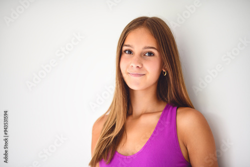 portrait of a 14 years old teen girl close to a white wall with colored shirt