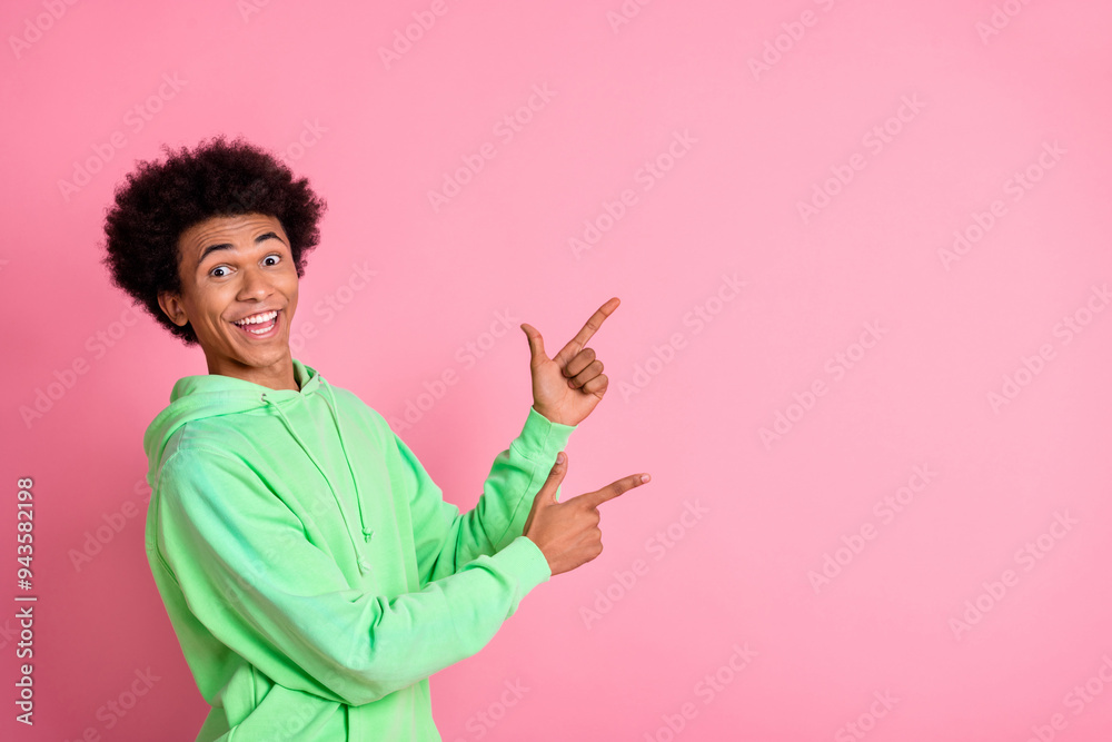 Portrait of nice young man indicate fingers empty space wear green hoodie isolared on pink color background Portrait of nice young man indicate fingers empty space wear green hoodie isolared on pink color background