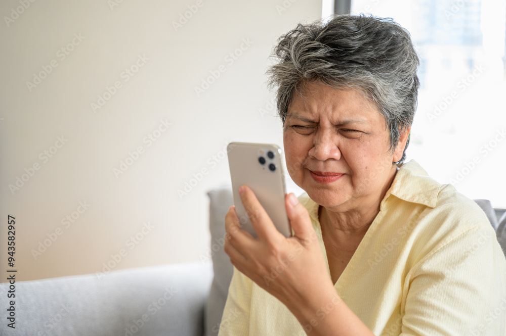 Senior people lifestyle health problem concept : Portrait photo of senior Asian woman has an eye long sighted problem trying to read message from smartphone monitor. Senior people lifestyle health problem concept : Portrait photo of senior Asian woman has an eye long sighted problem trying to read message from smartphone monitor.