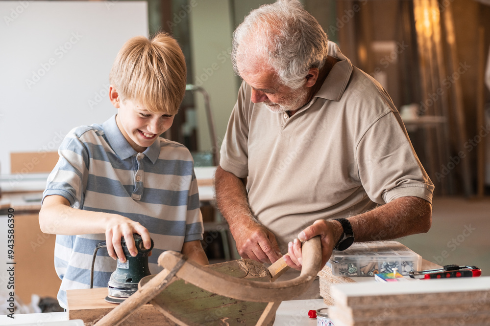 A grandfather teaches his grandson how to fix furniture in his carpenter workshop.
A grandfather teaches his grandson how to fix furniture in his carpenter workshop.