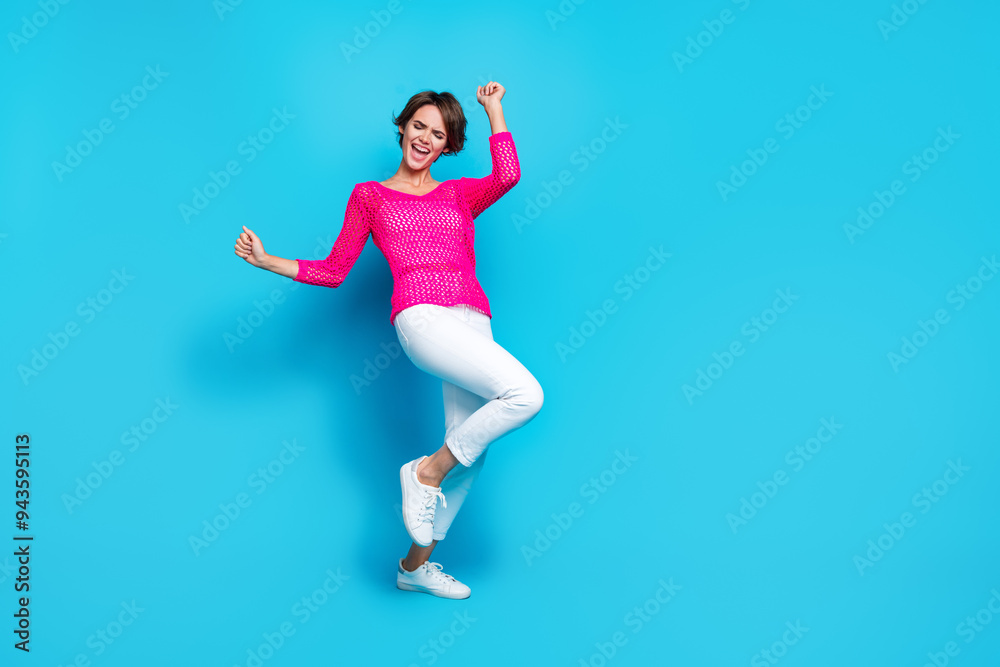 Full length photo of funky lucky lady dressed pink knitted shirt rising fists dancing empty space isolated blue color background Full length photo of funky lucky lady dressed pink knitted shirt rising fists dancing empty space isolated blue color background