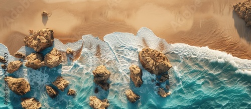 Top view of a rocky seashore with sandy texture and yellow desert dunes in the background ideal for showcasing summer products with a copy space image