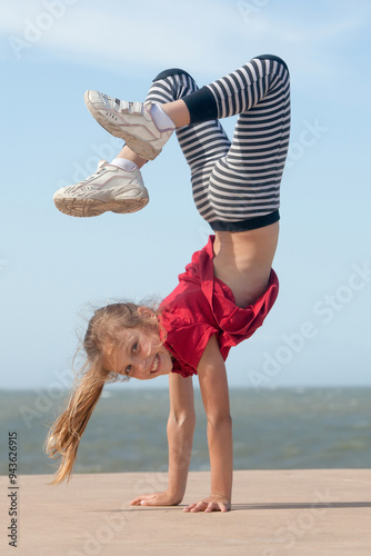 cheerful little girl doing cartwheel by the ocean