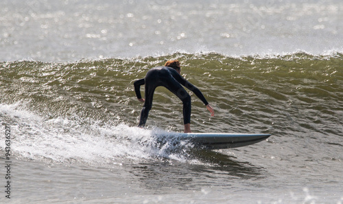 One surfer surfing on a wave wearing a full black wetsuit photo