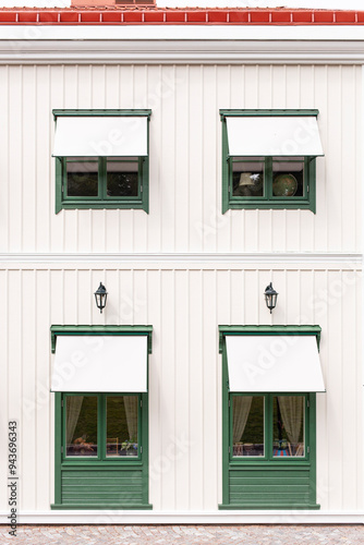 Grüne Fenster vor weißer Holzfassade. Skandinavische Architektur. Green windows in front of a white wooden façade. Scandinavian architecture.