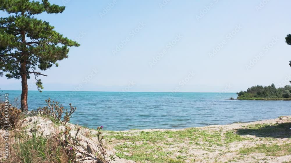 Drone fly from beach lake to water surface. Aerial footage Sevan lake in Armenia, Caucasus. Drone fly from grass, tree to lake. Touristic place in Armenia, West Asia. Drone fly from beach lake to water surface. Aerial footage Sevan lake in Armenia, Caucasus. Drone fly from grass, tree to lake. Touristic place in Armenia, West Asia.