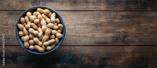 Bowl with peanuts in the shell and room for text on a table seen from above. with copy space image. Place for adding text or design