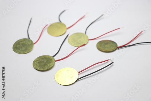 Piezoelectric discs with wires soldered made of copper on a white background