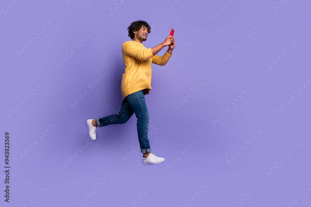 Photo of positive optimistic man wear trendy clothes use gadget run fast isolated on purple color background