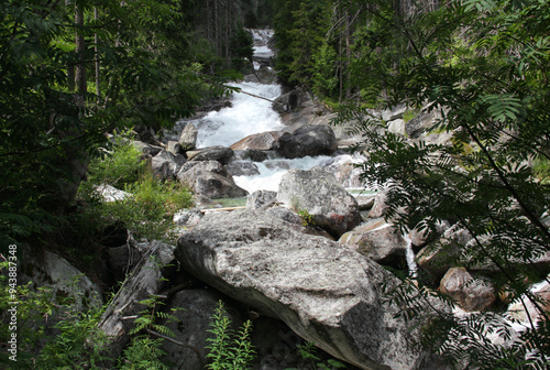 Landscape photo of the part of Vodopady Studeneho potoka waterfall surrounded by a dense pine forest near Stary Smokovec in Vysoke Tatry region, Slovakia	 photo