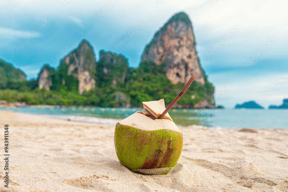 Coconut water drink with a straw on a rock by a tropical beach with turquoise water and palm trees in Phuket island, Thailand. Refreshment summer drink Coconut water drink with a straw on a rock by a tropical beach with turquoise water and palm trees in Phuket island, Thailand. Refreshment summer drink