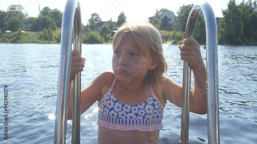 A teenage girl is going to plunge into the lake water. the child cannot decide to swim in the water