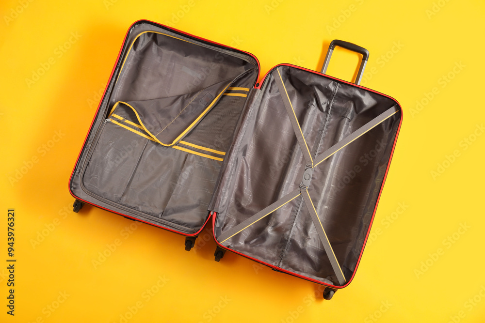 Open empty suitcase for travelling on yellow background, top view