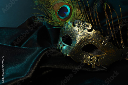 Beautiful carnival mask and peacock feather on black fabric, space for text photo