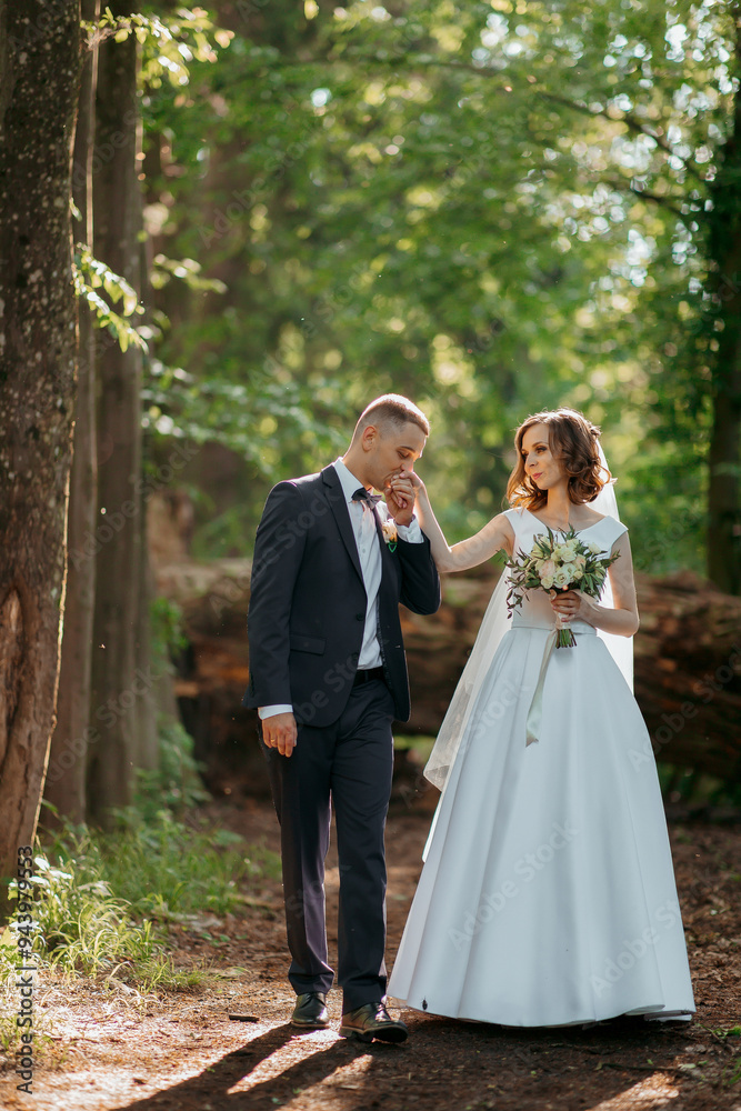 A bride and groom are walking through a forest, holding hands and smiling. The bride is wearing a white dress and the groom is wearing a suit. The scene is peaceful and romantic A bride and groom are walking through a forest, holding hands and smiling. The bride is wearing a white dress and the groom is wearing a suit. The scene is peaceful and romantic