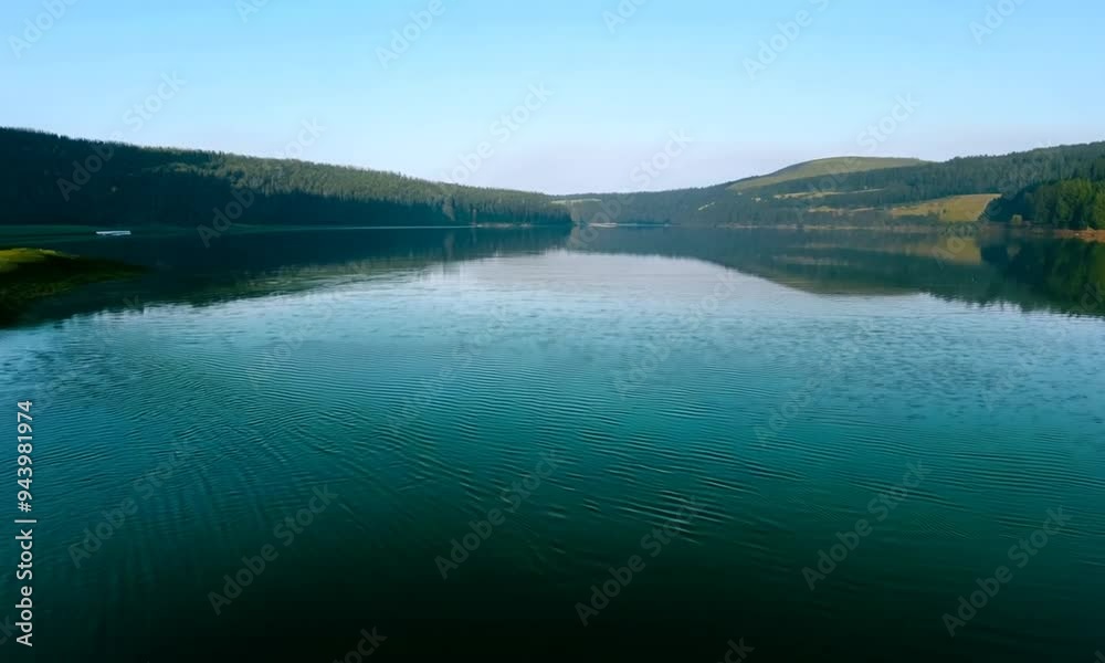 Spokojny widok nad jeziorem ukazuje gładką taflę wody, która idealnie odbija błękitne niebo i zielone brzegi. Spokojny widok nad jeziorem ukazuje gładką taflę wody, która idealnie odbija błękitne niebo i zielone brzegi.