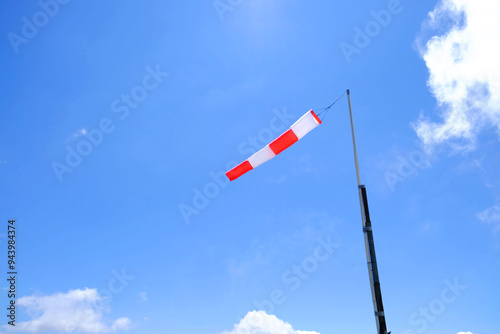 Striped windsock on pole against blue sky, space for text photo