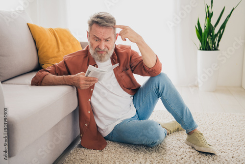 Tableau sur toile Full body photo of nice retired man sit floor upset read instruction wear brown