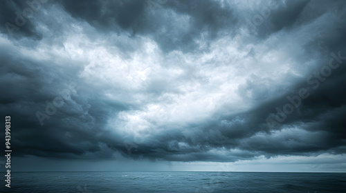 Dramatic dark clouds loom over calm ocean, creating moody and atmospheric scene. image evokes sense of anticipation and tranquility.