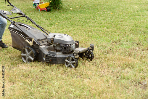 man cutting the grass with black lawnmower