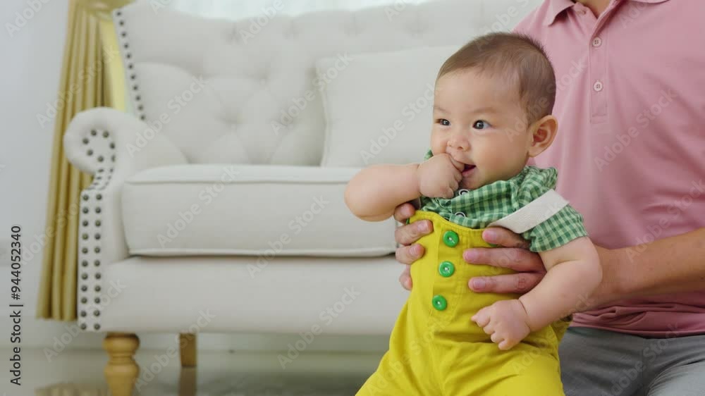 A man is holding a baby and smiling. The baby is wearing a yellow outfit. Scene is happy and joyful A man is holding a baby and smiling. The baby is wearing a yellow outfit. Scene is happy and joyful