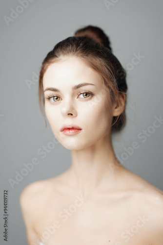 Beautiful young woman in white dress posing against a grey background