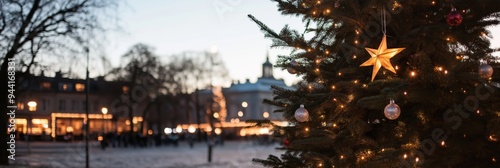 A beautifully decorated Christmas tree with lights set against the backdrop of an urban area softly lit in the evening.