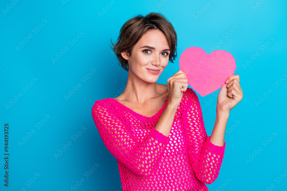 Photo of excited sweet lady dressed pink knitted shirt showing heart card empty space isolated blue color background Photo of excited sweet lady dressed pink knitted shirt showing heart card empty space isolated blue color background