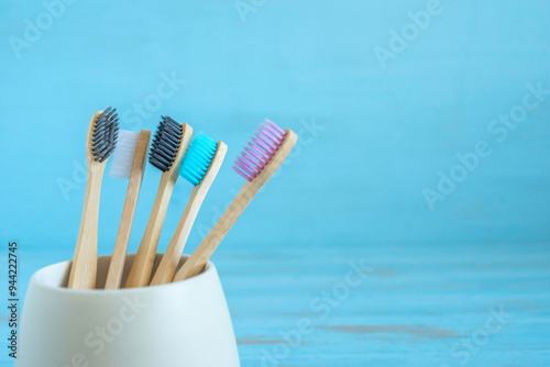 Toothbrush made of bamboo in ceramic holder on blue wooden background.