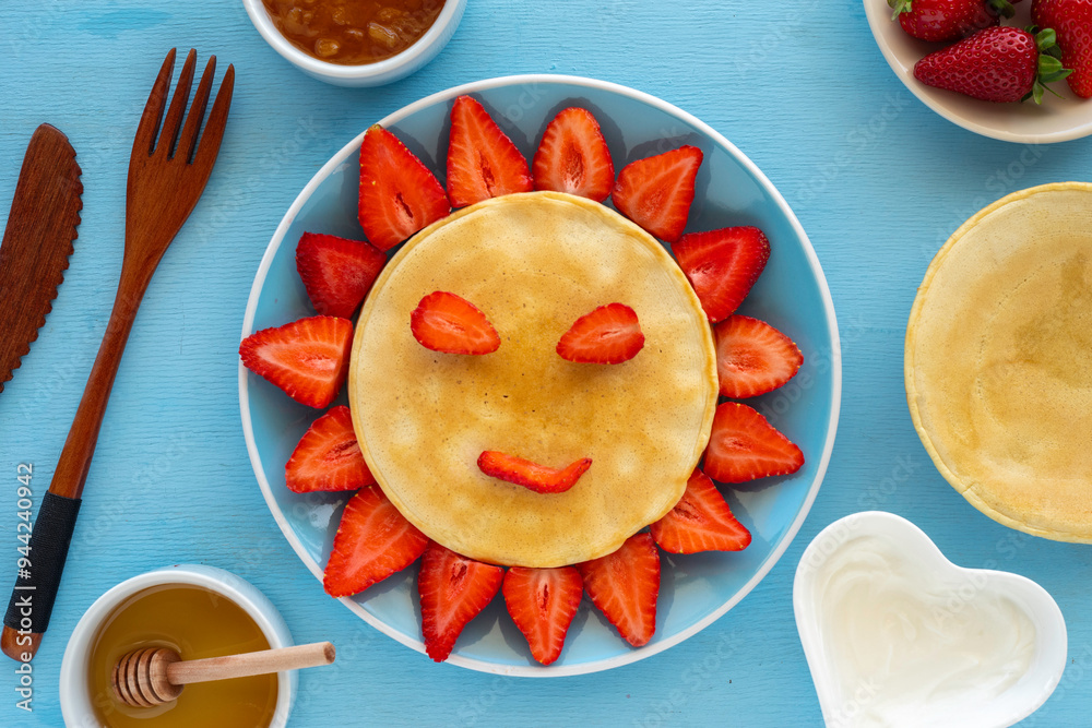 Φωτογραφία Pancakes and strawberries laid out in the form of flower on blue background