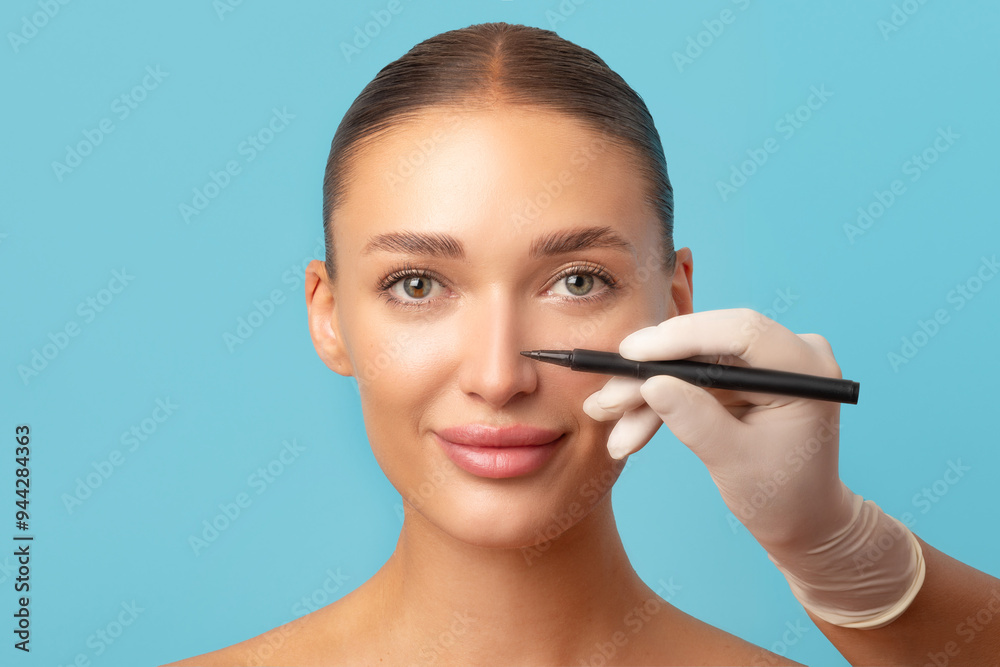 Facial plastic surgery concept. Beautiful woman on consultation at surgeon doctor making marks on female face over blue studio background Facial plastic surgery concept. Beautiful woman on consultation at surgeon doctor making marks on female face over blue studio background