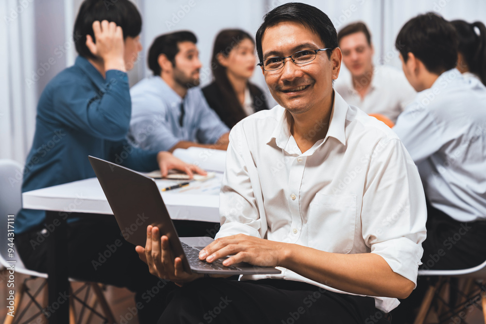 Confidence and happy smiling businessman portrait with background of his colleague and business team working in office. Office worker teamwork and positive workplace concept. Prudent Confidence and happy smiling businessman portrait with background of his colleague and business team working in office. Office worker teamwork and positive workplace concept. Prudent