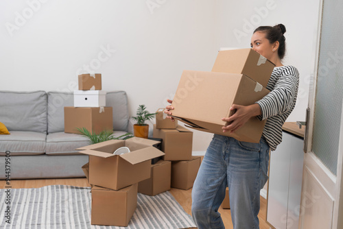Photography Woman holds heavy boxes with personal items standing in bright premise of new ac