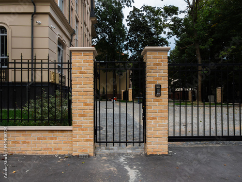 black metal fence with gate and yellow facing brick photo