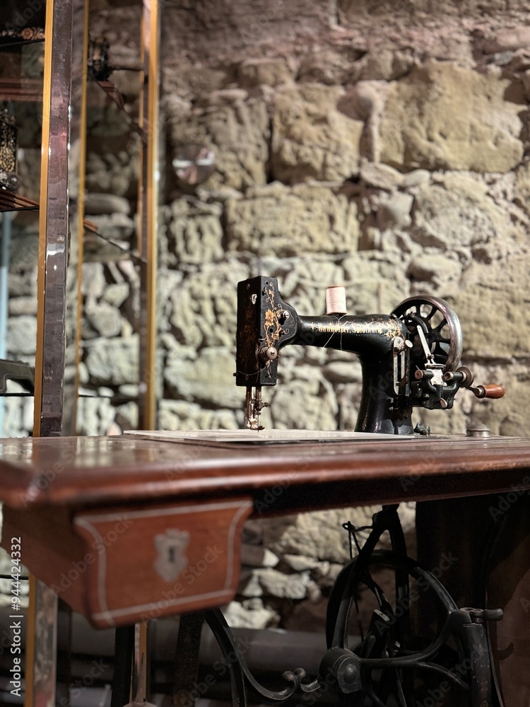Fototapeta premium A collection of antique sewing machines displayed in a vintage setting, showcasing intricate details and craftsmanship. These machines represent a bygone era of sewing and textile production