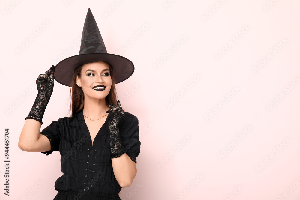 Young woman dressed for Halloween as witch on light background