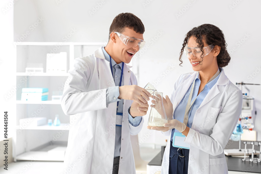 Young chemists doing reaction in laboratory Young chemists doing reaction in laboratory