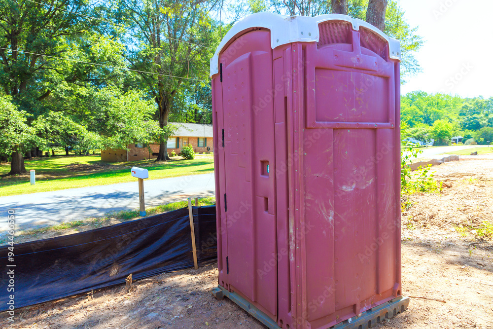 An on site construction site is equipped with portable plastic bio toilet cabin stalls during construction of house