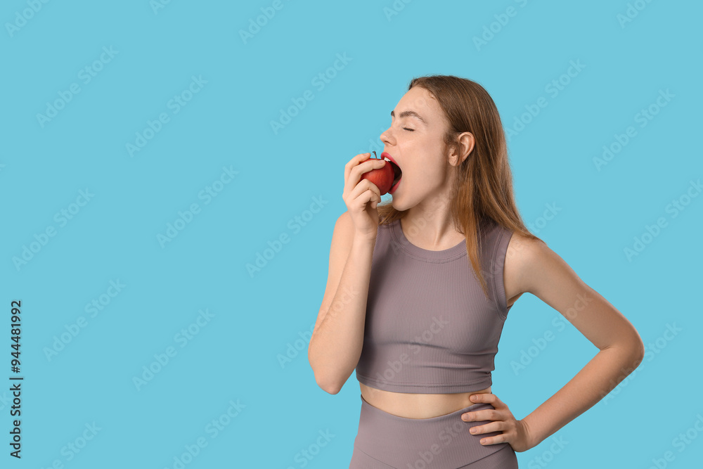 Sporty young woman eating apple on blue background. Diet concept Sporty young woman eating apple on blue background. Diet concept