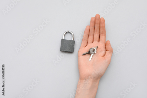 Hands with padlock and keys on grey background