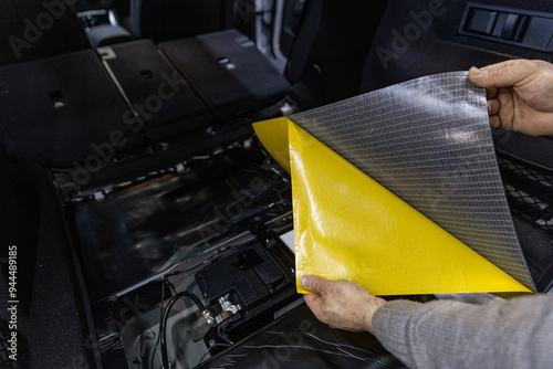 Process of installation of soundproofing material to inside of car. Auto sound insulation.  Audio and vibration isolation. Soft material. Dismantled car. Additional equipment.